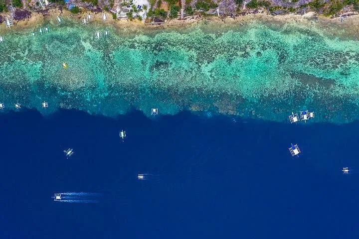 Aerial view of boats in blue water near coral reef