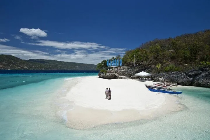 Two people standing on a pristine white sandbar